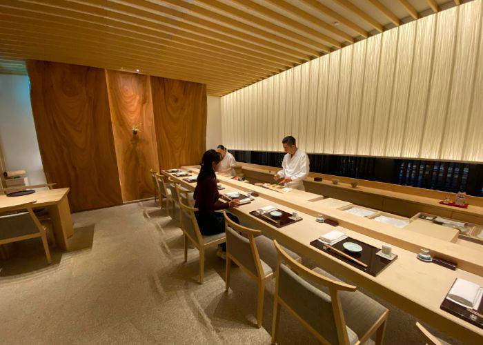 A guest dining at Musashi by Aman, watching the chef prepare Edomae sushi.